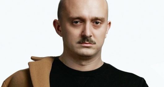 Vald chauve avec une moustache, sa réaction pleine d'humour